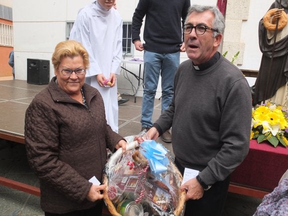 Una vecina recoge una cesta, premio del sorteo de San Antón.