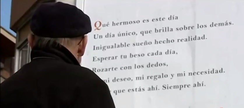 Un hombre lee el anuncio puesto en la valla. 