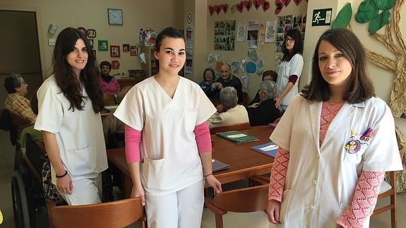 La directora del centro de día, Pilar Pérez, a la derecha, posa en una estancia del centro junto a tres compañeras y varios usuarios. 