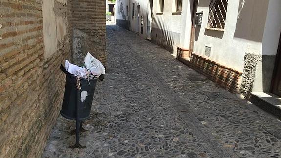 Una papelera rebosante de basura en una calle del barrio 