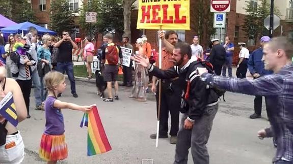 Una niña con la bandera gay le planta cara en silencio a un fanático homófobo religioso