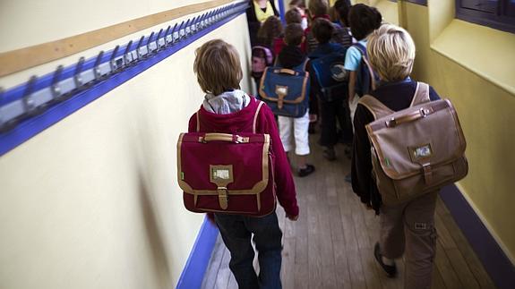 Escolares caminan hacia sus aulas, bien pertrechados ya con abrigos y las mochilas repletas de libros y material escolar. :