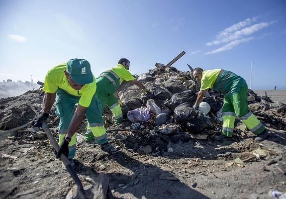 Trabajadores municipales de la limpieza se encargan de dejar limpia la playa después de San Juan, en una imagen de archivo. 