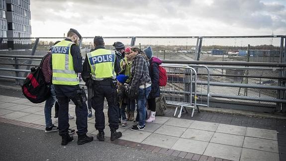 Varios policías suecos hablan con un grupo de refugiados en la estación de Malmoe, Suecia. 
