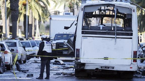 Policías forenses tunecinos inspeccionan los restos de un autobús tras el atentado contra varios guardias presidenciales que se encontraban a bordo del vehículo, en Túnez.
