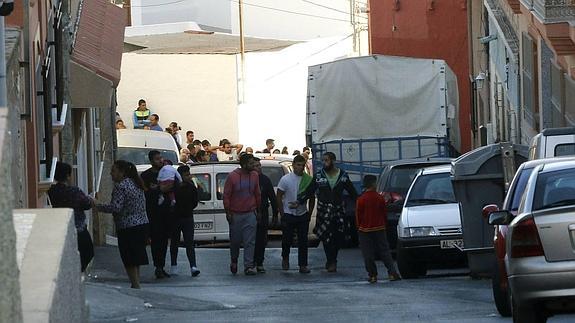 Un grupo de vecinos se agolpan frente a la vivienda que la Guardia Civil ha localizado los cadáveres.