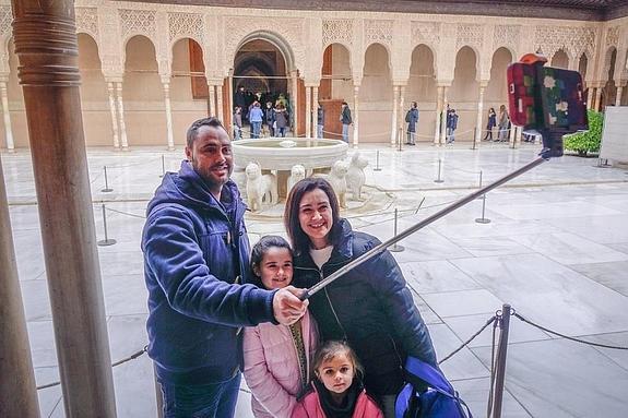 Una familia mallorquina de visita en Granada se autorretrata con el 'paloselfi' en el Patio de los Leones de la Alhambra.