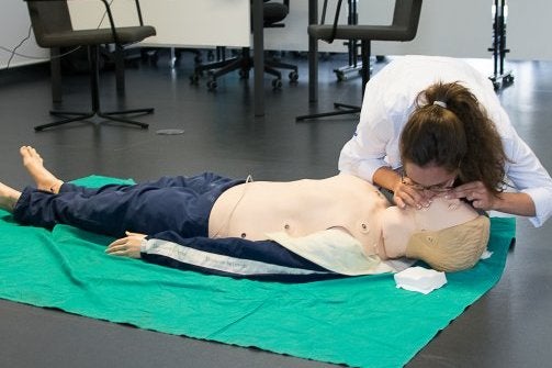 Una estudiante practica el boca a boca a un muñeco.
