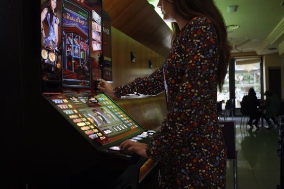 Una mujer juega con una máquina tragaperras en una cafetería de la capital.