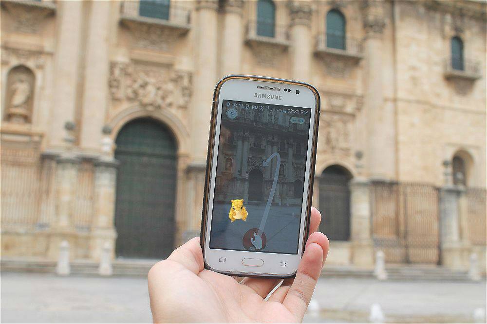 Un jienense sostiene su smartphone con el juego ante la Catedral de Jaén. 