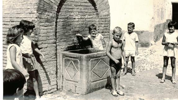 Unos niños se refrescan con el agua de un aljibe en un caluroso día de verano.