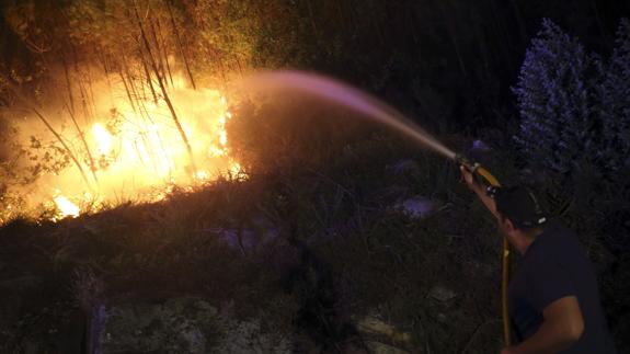 Un bombero trata de acabar un un incendio en Galicia. 