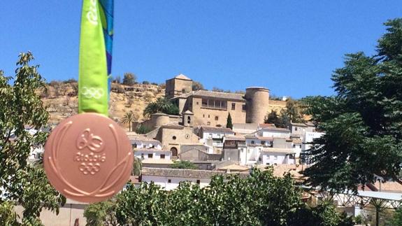 El jugador muestra la medalla de bronce de baloncesto con la localidad de fondo.  