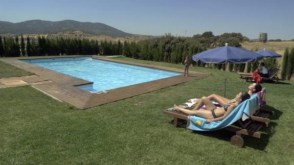 Una pareja de turistas toma el sol en la piscina del complejo rural La Aldeilla en Aldeaquemada.  