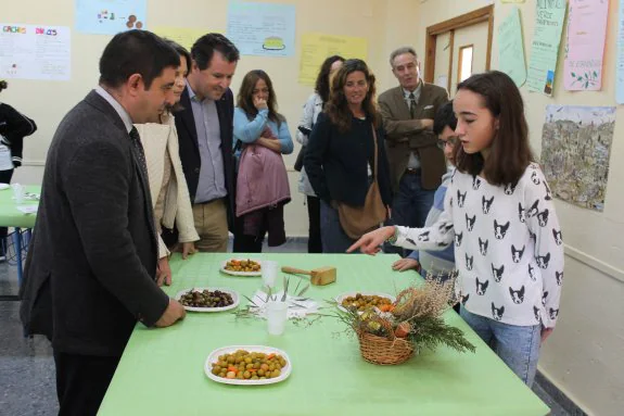 Una de las alumnas del IES Fuente de la Peña ofrece a las autoridades olivas aliñadas con aceitunas del olivo del centro.