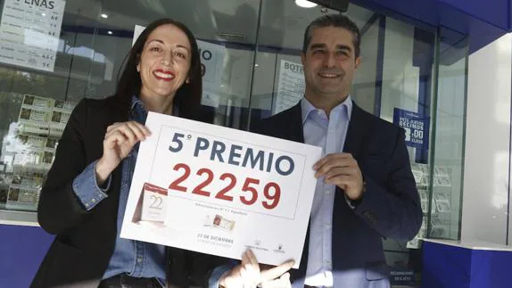 El dueño de la administración de lotería número 3 de Aguadulce, Juan José Rodero, junto a la empleada Belén Ortíz, sostienen el cartel con el número 22.259 premiado con un quinto premio en el Sorteo Extraordinario de la Lotería de Navidad.