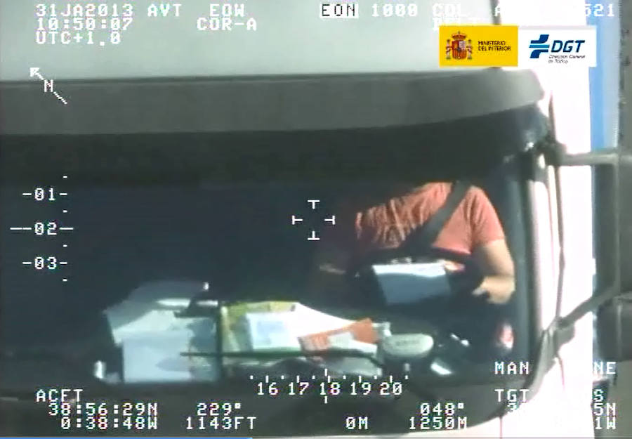 El chófer de un camión, captado por el helicóptero de Tráfico mientras rellena unos informes conduciendo.