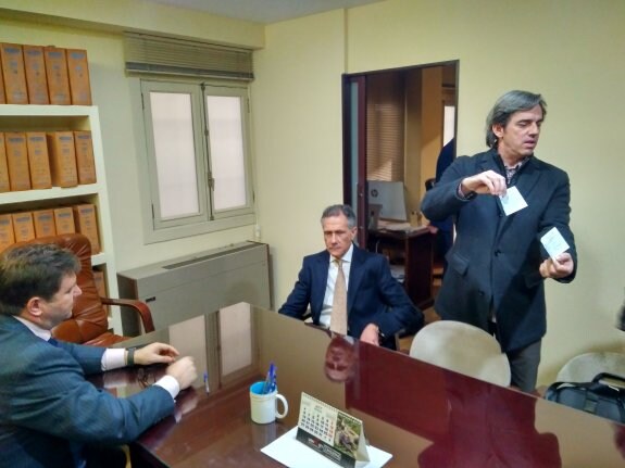 Andrés Rodríguez, del equipo de Tomás Membrado, muestra los dos cheques del traspaso, a los medios, ante el empresario jienense y Juan Miguel Hitos.