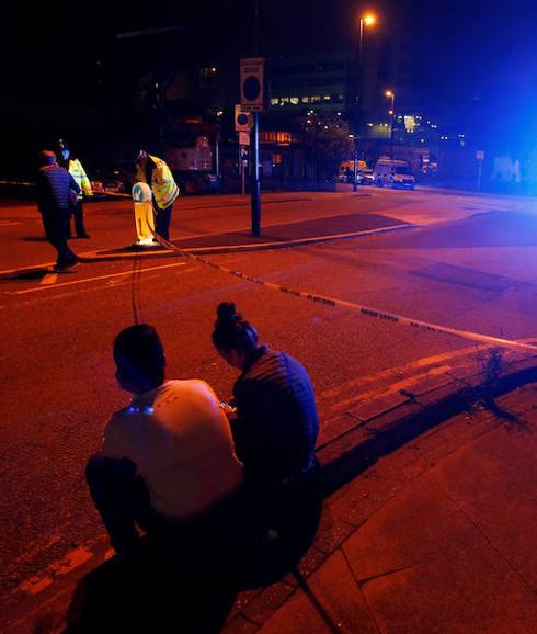 Asistentes al concierto hablan con un policía.
