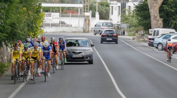 Grupo de ciclistas en carretera compartiendo calzada con los vehículos.
