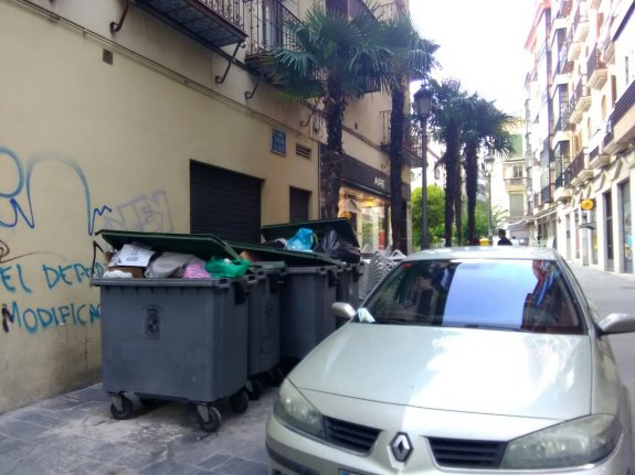 Contenedores de basura y coche sobre la acera en San Ildefonso.