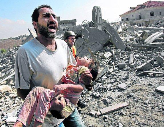 Un padre sostiene en brazos el cuerpo inerte de su hijo tras el bombardeo de su casa en Qana (Líbano) por la aviación israelí, en julio de 2006.