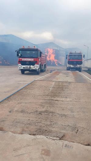 Dos camiones de bomberos con las llamas de fondo