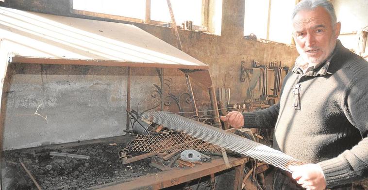 Olegario Villoria sostiene un paso de una escalera de caracol en el taller donde elabora sus creaciones y encargos.