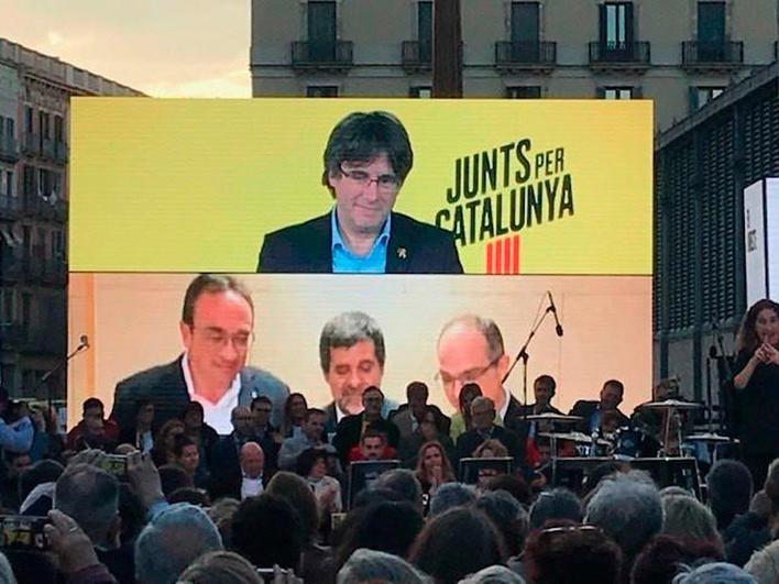 Acto político en el que aparece una fotografía de Puigdemont