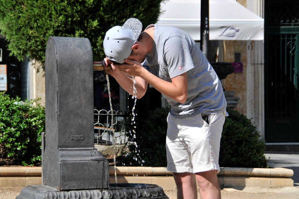 Un joven se refresca en una fuente en Salamanca.