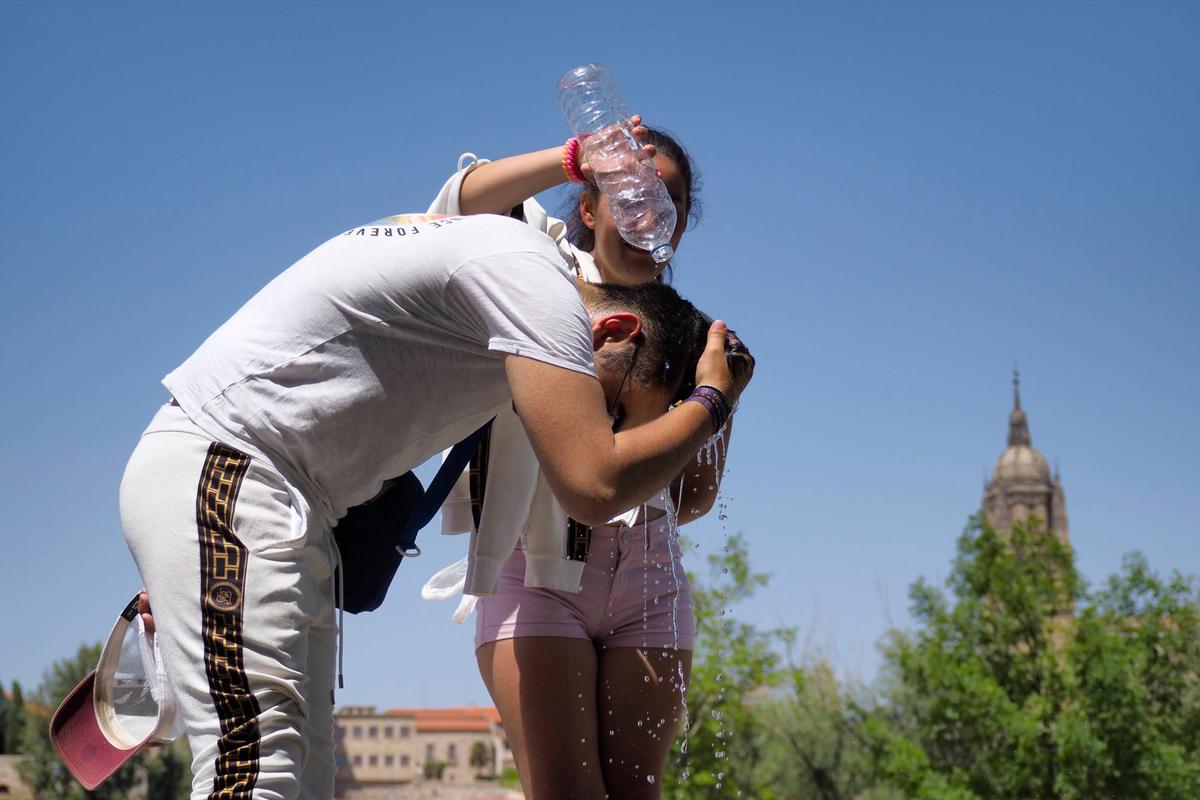 Dos personas se refrescan con agua en Salamanca.