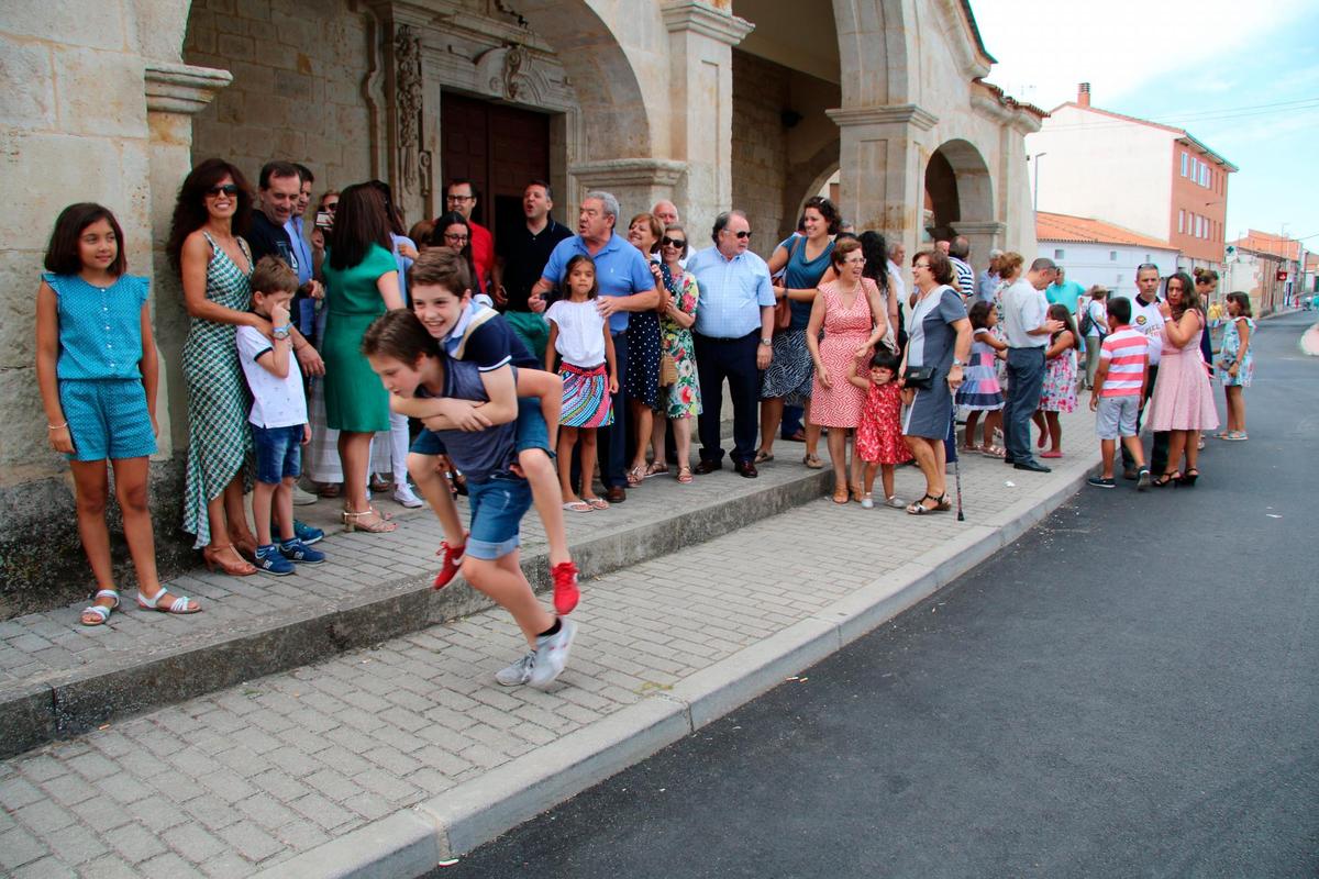 Vecinos de la localidad a la puerta de la parroquia de Santa Elena mientras los niños juegan.