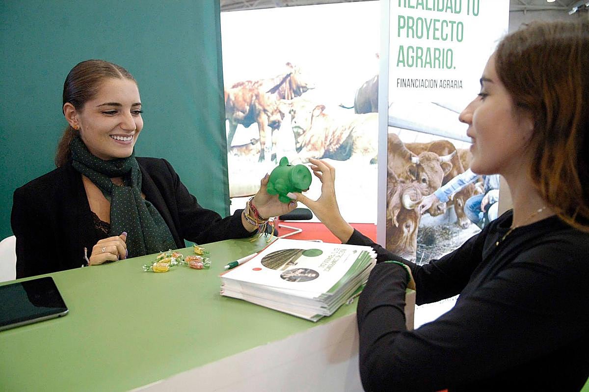 Una visitante recoge un obsequio de un expositor de la Feria