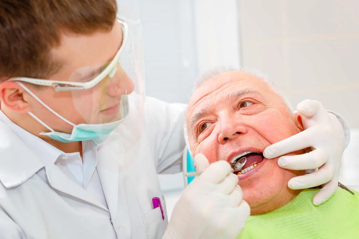 Un dentista revisa la dentadura de un anciano.