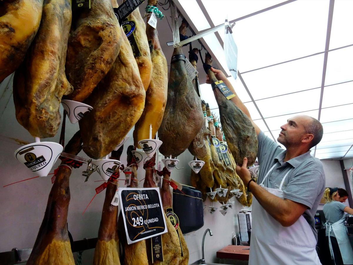 Un carnicero descuelga un jamón ibérico.