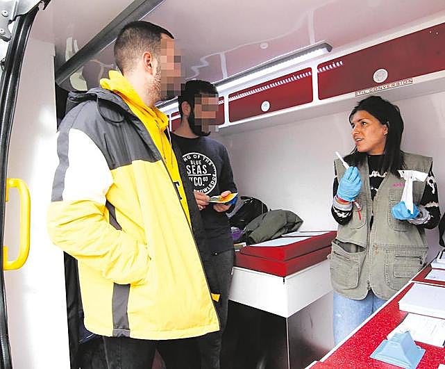 Dos jóvenes reciben información sobre el VIH en un vehículo asistencial de Cruz Roja en el Campus.