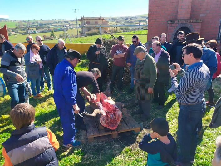 Imagen del destripe del cerdo rodeado por todos los asistentes