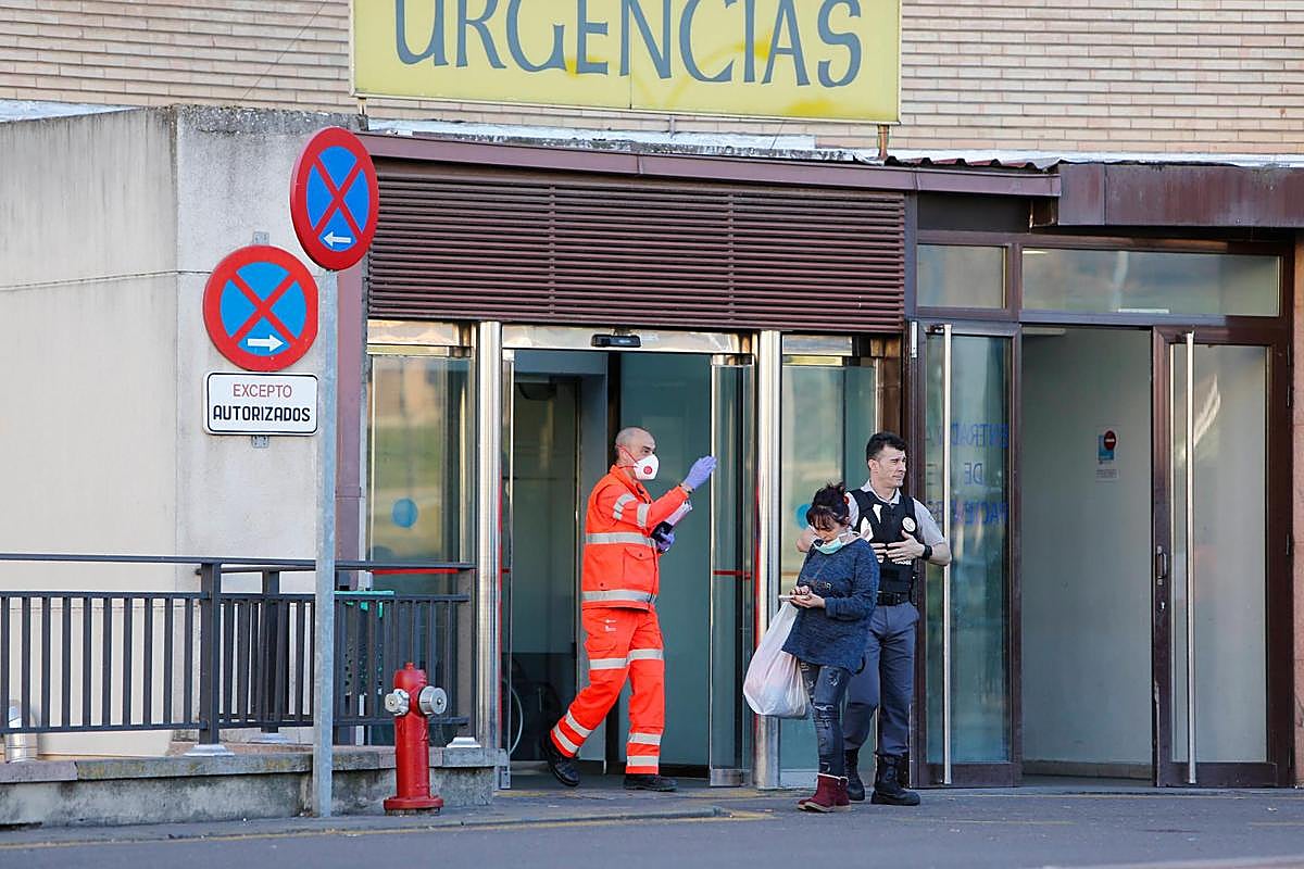 Un sanitario y una mujer con mascarillas a la puerta de las Urgencias del Hospital Clínico de Salamanca.