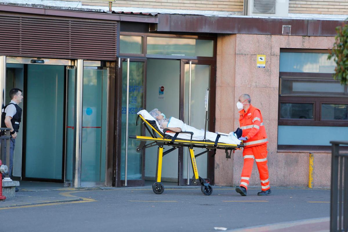 Un sanitario traslada a una mujer, ambos con mascarillas, en el Hospital Clínico de Salamanca.