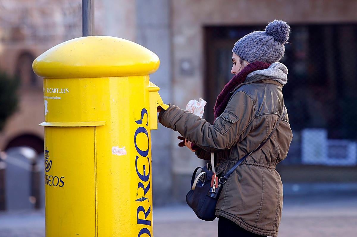 Una joven introduce una carta en un buzón.