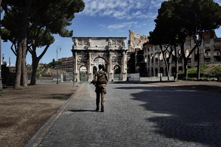 Un militar frente al arco de Trajano en Roma.