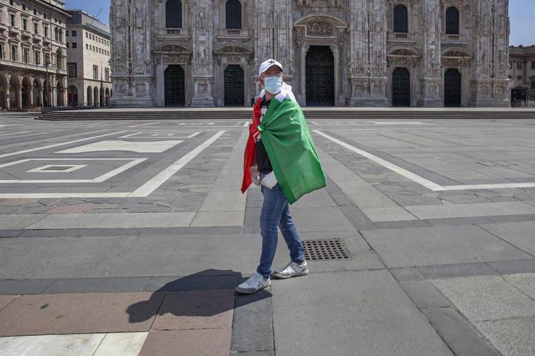 Un hombre con la bandera de Italia y mascarilla frente a la catedral de Milán.