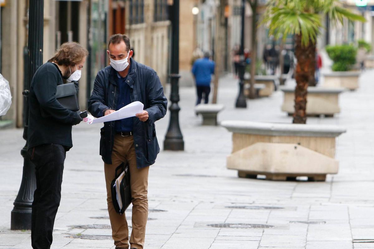 Dos personas con mascarilla miran unos documentos en el centro de Salamanca