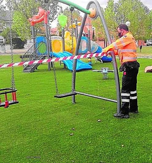 Un miembro de protección civil reforzando el cierre de un columpio.