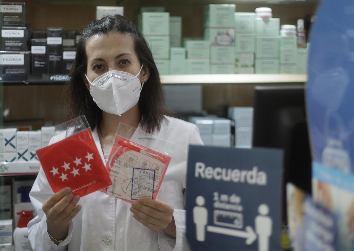 Una farmacéutica muestra una mascarilla en la Farmacia CEA, una de las 2.882 farmacias madrileñas.