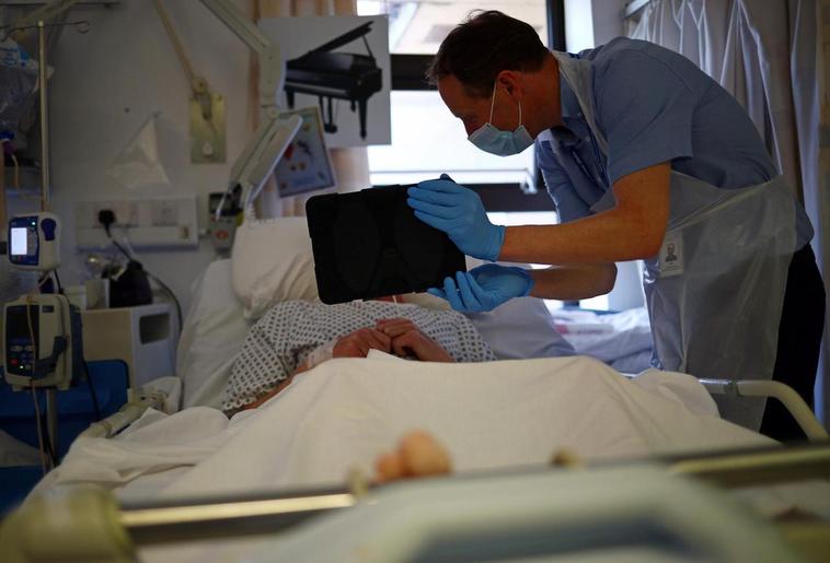 Un sanitario haciendo videollamada junto a un paciente.