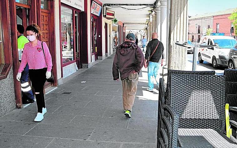 Viandantes pasando a media mañana por los soportales de la céntrica plaza de España, de Peñaranda.