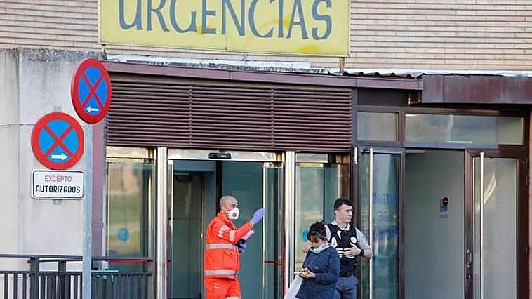 Un sanitario y una mujer con mascarillas a la puerta de las Urgencias del Hospital Clínico de Salamanca.