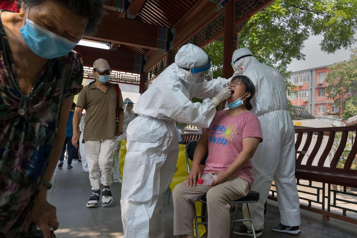 Sanitarios realizando la prueba del COVID a una mujer en Pekín.