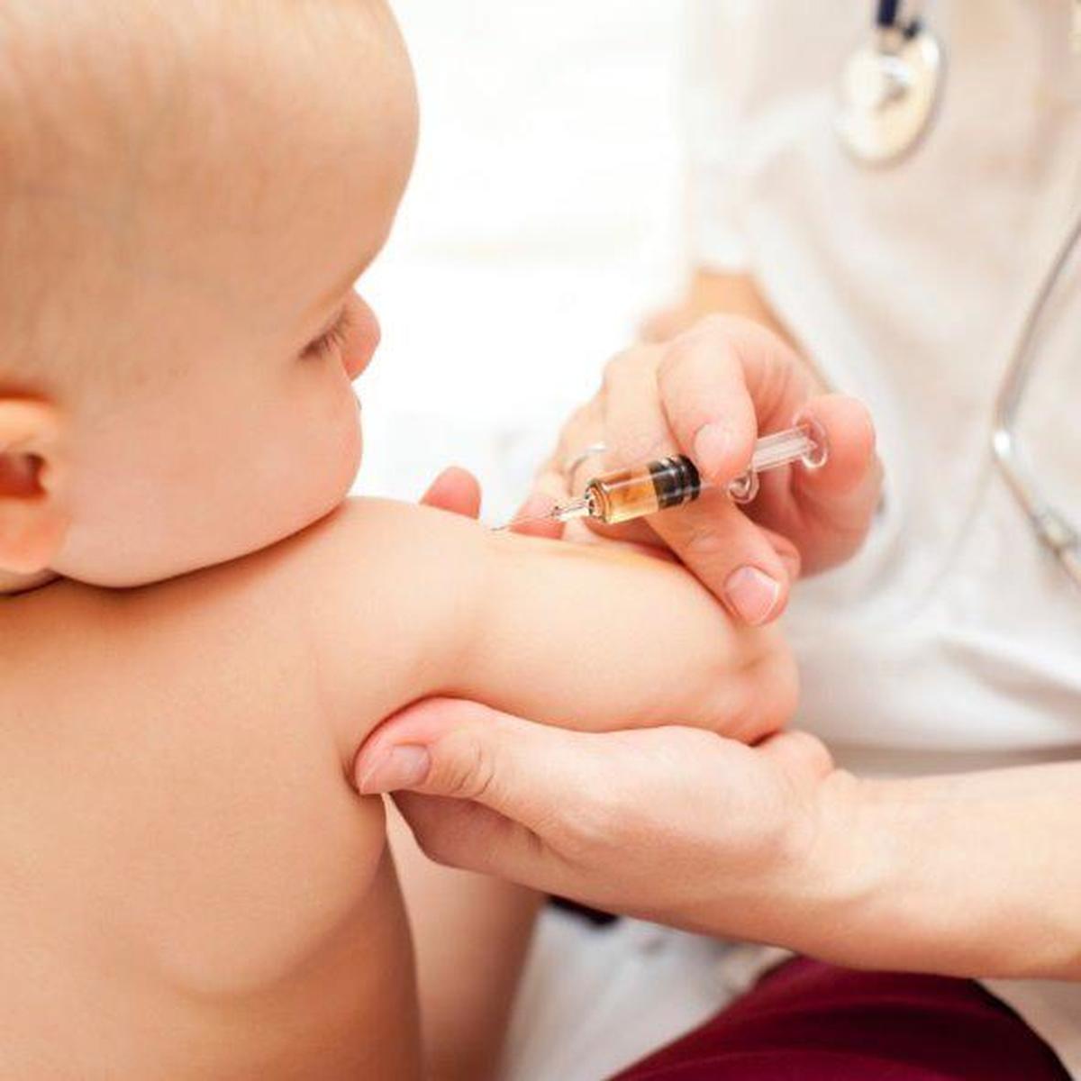 Un pediatra le inyecta una vacuna a un bebé.